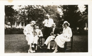 Kvinner og menn sitter på stoler i en park